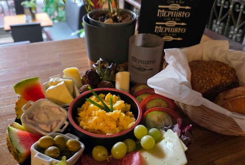 Rustikales Frühstück im Mephisto Uelzen mit Rührei, Fleischsalat, Käse, Aufschnitt, Oliven und frischen Brötchen.