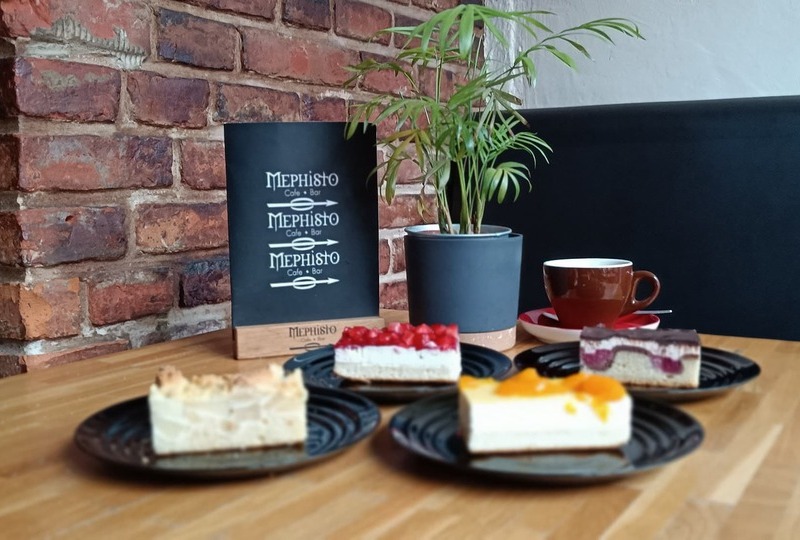 Ein Stück Kuchen und eine Tasse Kaffee im Mephisto Uelzen auf einem Holztisch – gemütliche Café-Atmosphäre.
